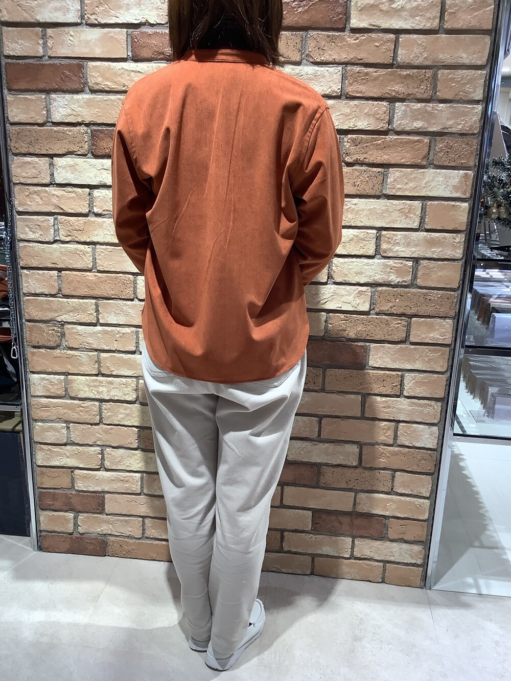 オレンジ系のシャツ/ブラウス、グリーン系のニット/セーターを着用したレディースの冬コーディネートの3枚目の写真