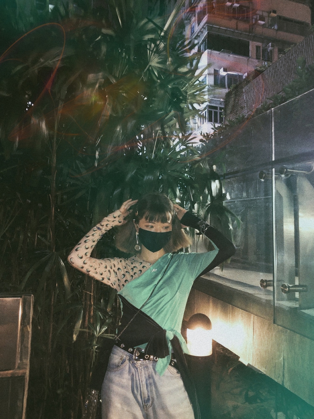 グリーン系のトップス、ブラック系のブーツ、シルバー系のイヤリングを着用したレディースの夏コーディネートの3枚目の写真