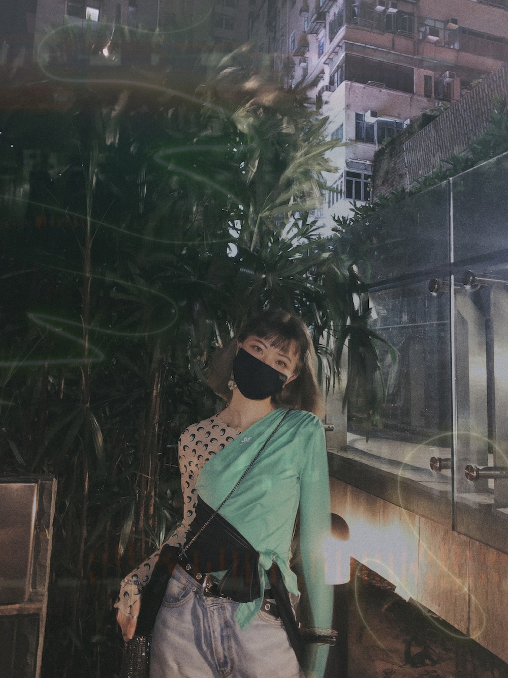 グリーン系のトップス、ブラック系のブーツ、シルバー系のイヤリングを着用したレディースの夏コーディネートの2枚目の写真