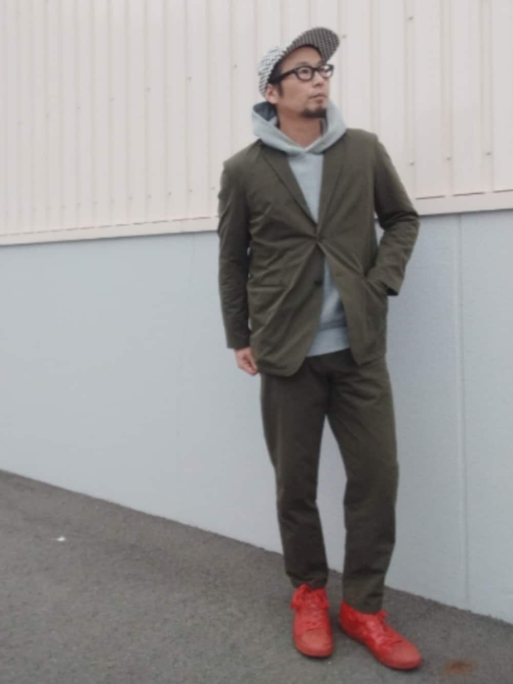 グリーン系のセットアップ、グレー系のパーカー、レッド系のスニーカーを着用したメンズの秋コーディネートの2枚目の写真