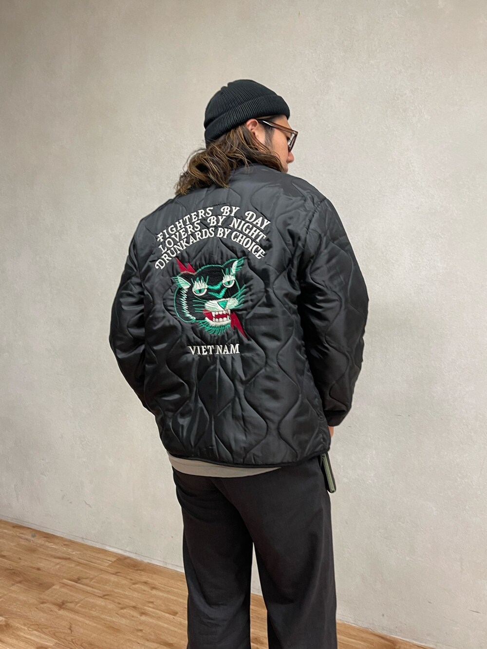 ブラック系のミリタリージャケット、ブラック系のバッグ、ブラック系のスラックスを着用したメンズの秋コーディネートの2枚目の写真