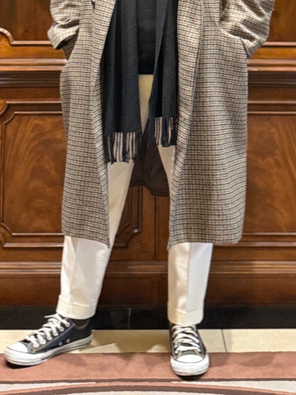 ベージュ系のステンカラーコート、ホワイト系のスラックス、ブラック系のスニーカーを着用したメンズの冬コーディネートの3枚目の写真