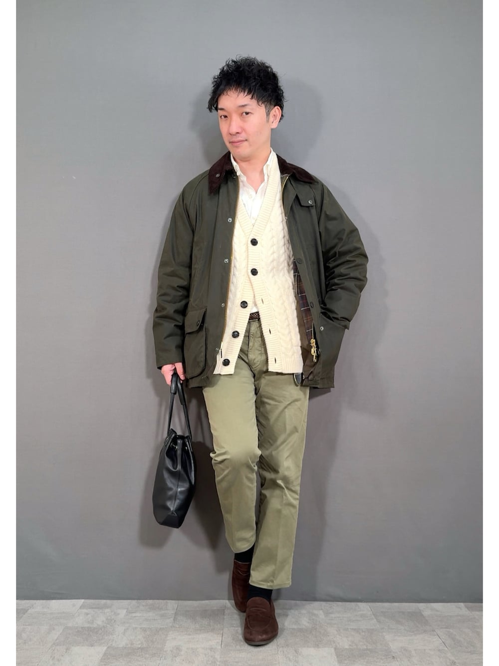 ホワイト系のカーディガン/ボレロ、グリーン系のスラックス、ブラウン系のローファーを着用したメンズの冬コーディネートの5枚目の写真