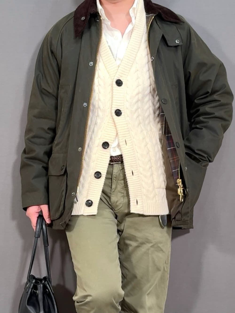 ホワイト系のカーディガン/ボレロ、グリーン系のスラックス、ブラウン系のローファーを着用したメンズの冬コーディネートの2枚目の写真