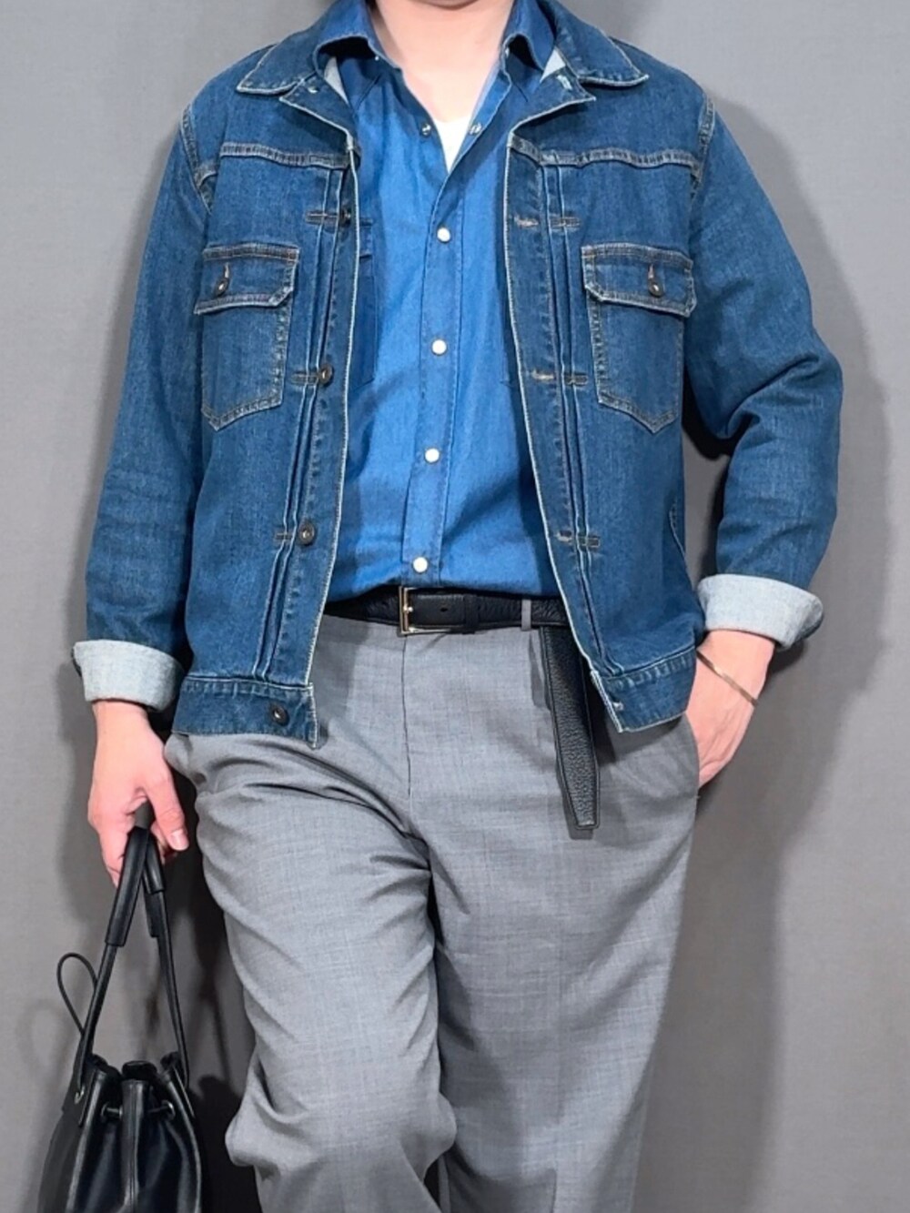 ブルー系のデニムジャケット、グレー系のスラックス、ホワイト系のスニーカーを着用したメンズの春コーディネートの2枚目の写真