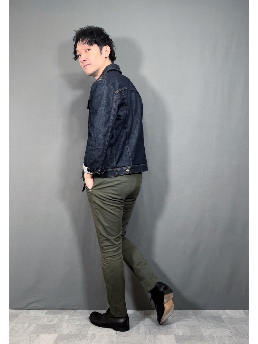 ブルー系のデニムジャケット、グリーン系のスラックス、ブラック系のドレスシューズを着用したメンズの春コーディネートの4枚目の写真
