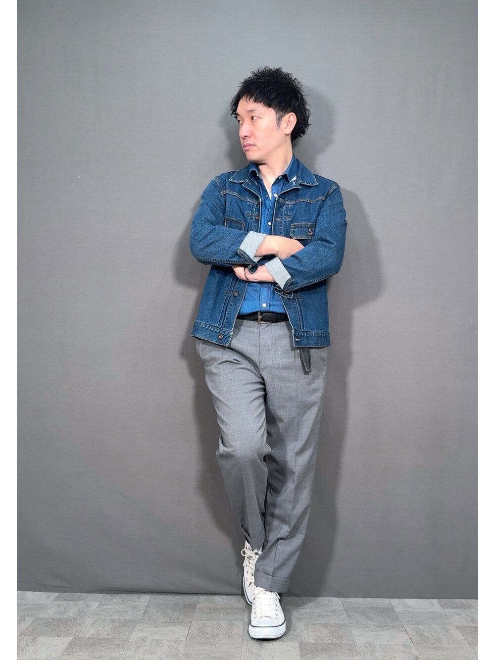 ブルー系のデニムジャケット、グレー系のスラックス、ホワイト系のスニーカーを着用したメンズの春コーディネートの4枚目の写真