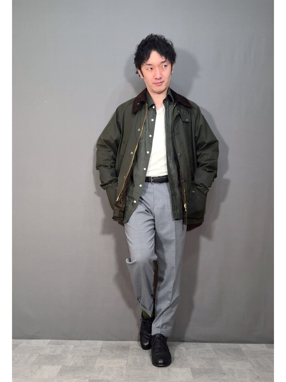 グリーン系のジャケット/アウター、グレー系のスラックス、ブラック系のドレスシューズを着用したメンズの春コーディネートの5枚目の写真