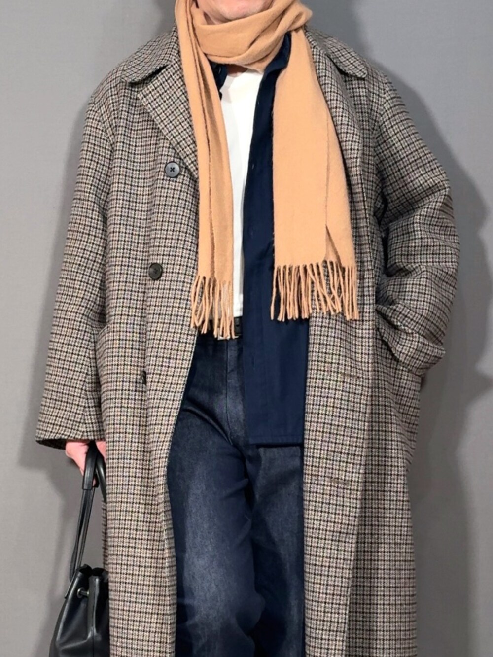 ベージュ系のステンカラーコート、ブルー系のデニムパンツ、ホワイト系のスニーカーを着用したメンズの冬コーディネートの2枚目の写真