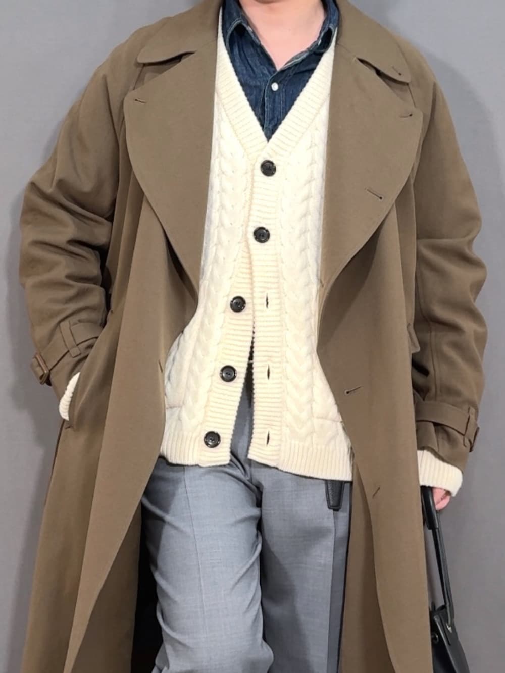 ホワイト系のカーディガン/ボレロ、グリーン系のトレンチコート、グレー系のスラックスを着用したメンズの冬コーディネートの2枚目の写真