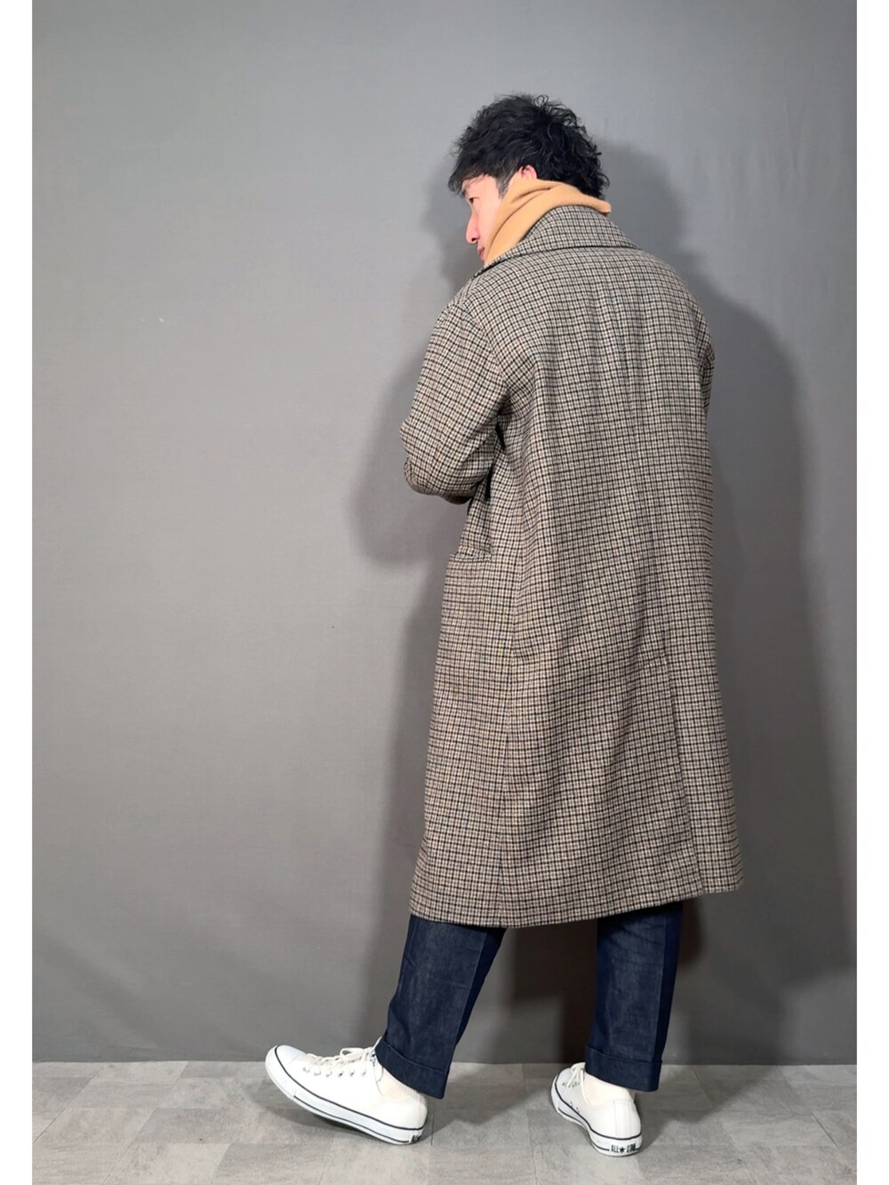 ベージュ系のステンカラーコート、ブルー系のデニムパンツ、ホワイト系のスニーカーを着用したメンズの冬コーディネートの4枚目の写真