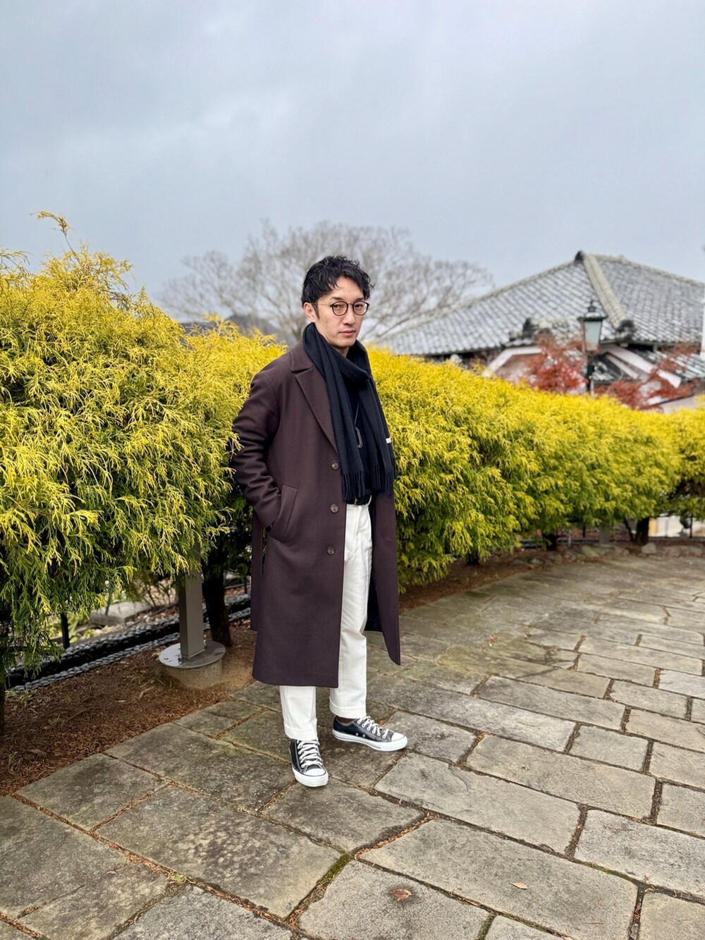 ブラウン系のジャケット/アウター、ホワイト系のスラックス、ブラック系のスニーカーを着用したメンズの冬コーディネートの2枚目の写真