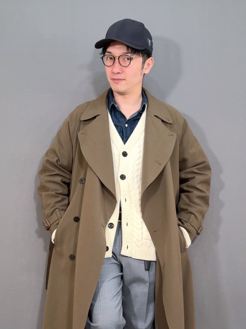 ホワイト系のカーディガン/ボレロ、グリーン系のトレンチコート、グレー系のスラックスを着用したメンズの冬コーディネートの5枚目の写真