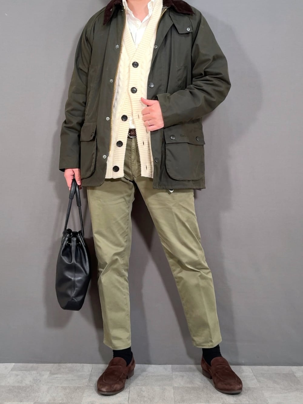 ホワイト系のカーディガン/ボレロ、グリーン系のスラックス、ブラウン系のローファーを着用したメンズの冬コーディネートの4枚目の写真