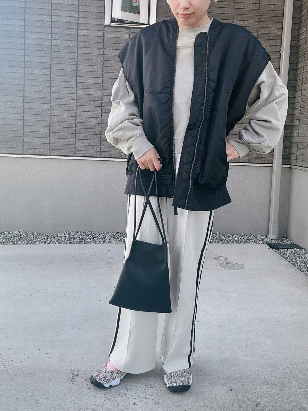 ブラック系のダウンベスト、グリーン系のスウェット、ブラック系のトートバッグを着用したレディースの秋コーディネートの4枚目の写真