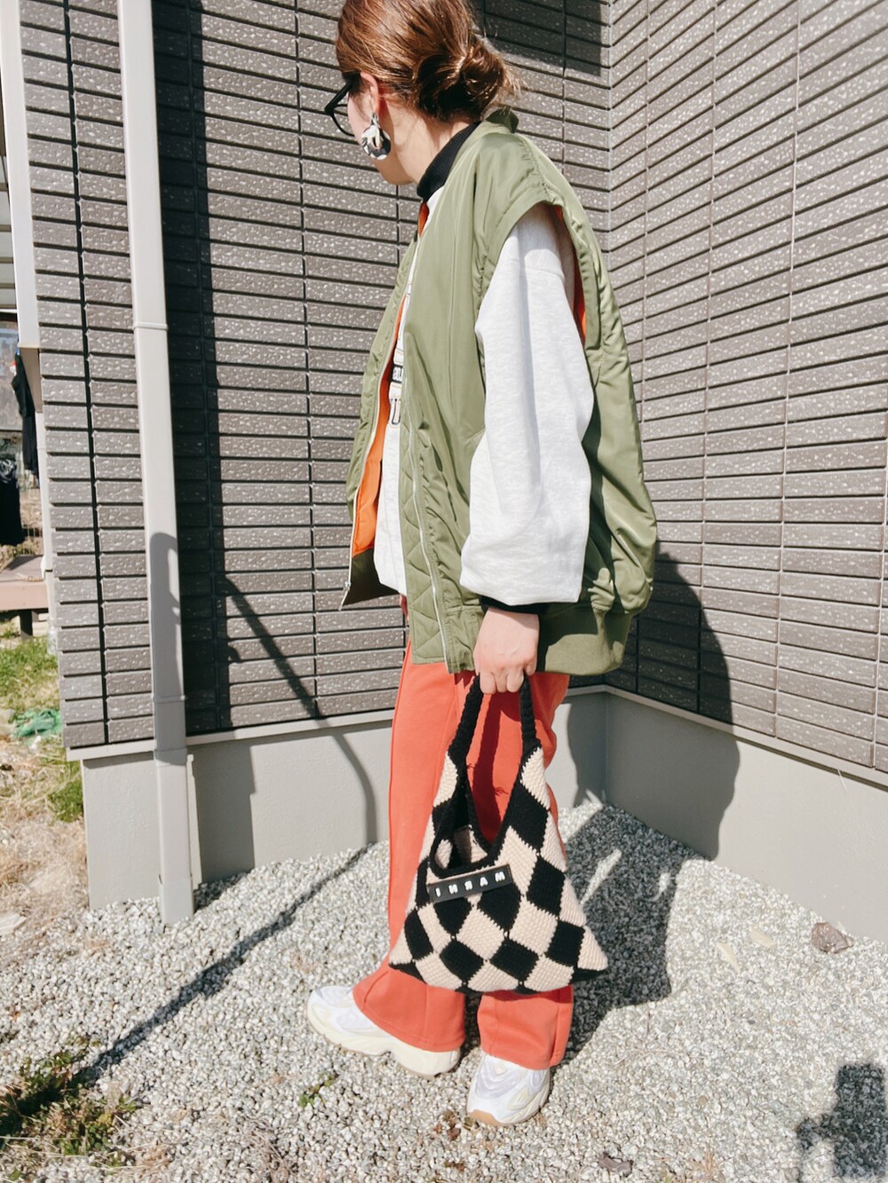 グリーン系のMA-1、ブラック系のTシャツ/カットソー、オレンジ系のその他パンツを着用したレディースの冬コーディネートの2枚目の写真