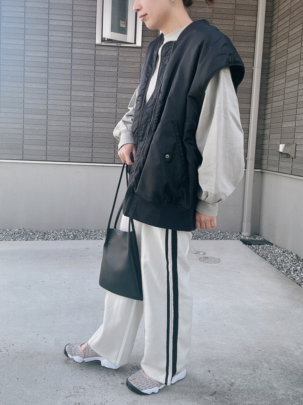 ブラック系のダウンベスト、グリーン系のスウェット、ブラック系のトートバッグを着用したレディースの秋コーディネートの2枚目の写真