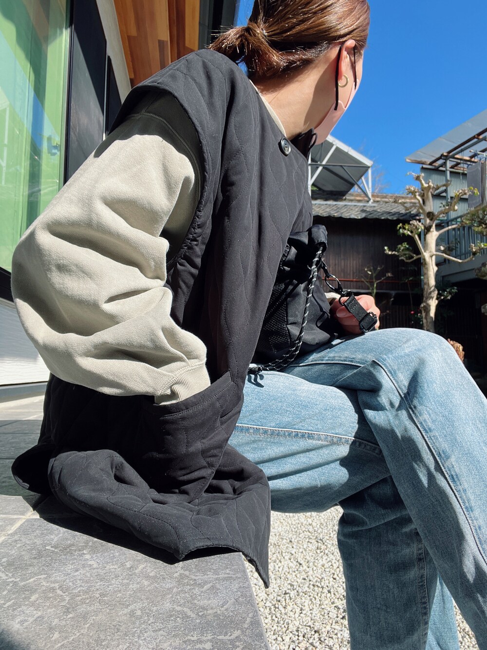 ブラック系のベスト、グリーン系のスウェット、ブルー系のデニムパンツを着用したレディースの春コーディネートの3枚目の写真