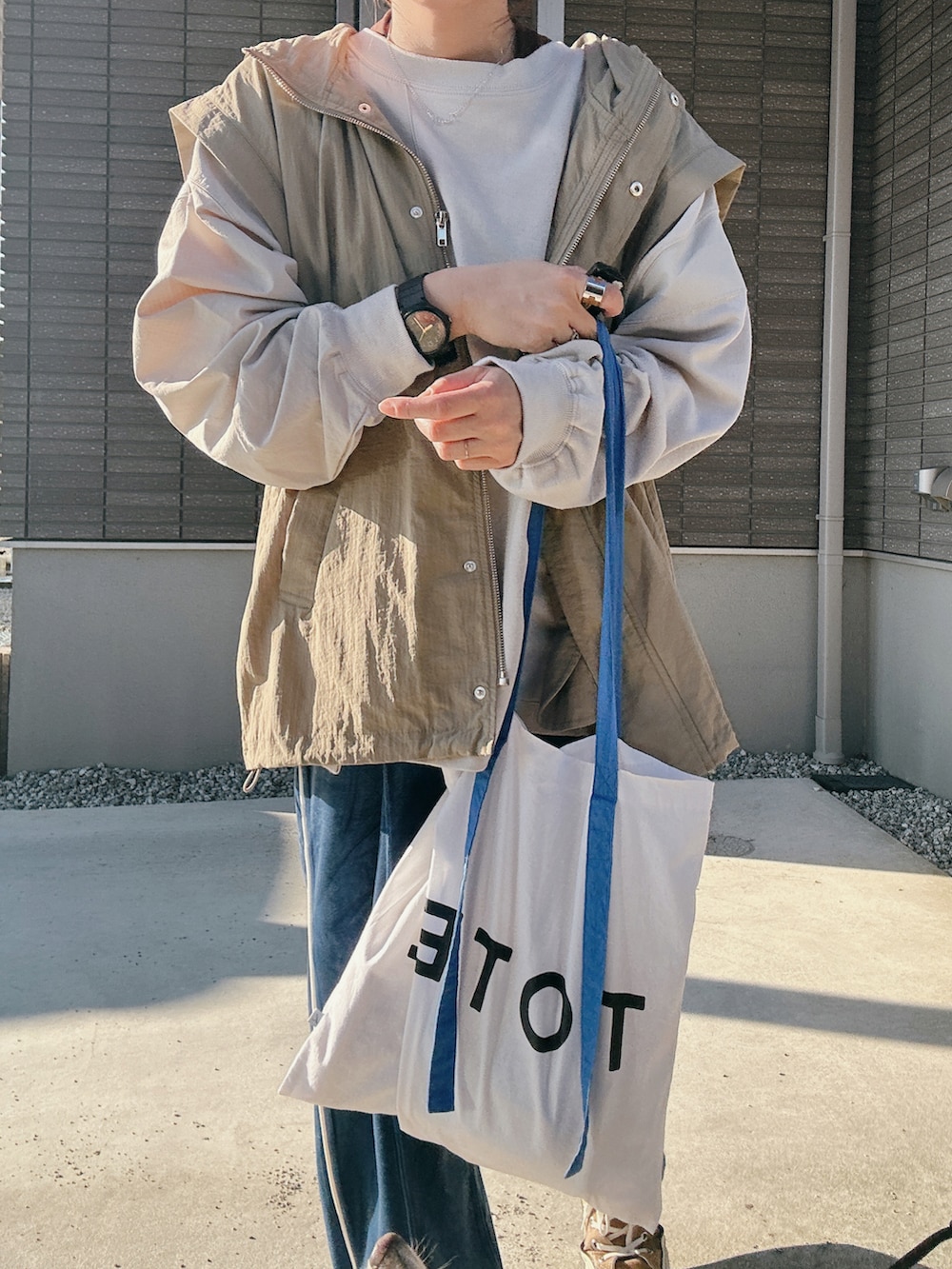 グレー系のスウェット、ブルー系のトートバッグ、ブラウン系のスニーカーを着用したレディースの秋コーディネートの3枚目の写真