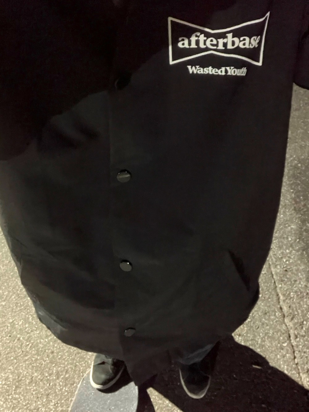 ブラック系のナイロンジャケット、ブラック系のスニーカー、グレー系のパーカーを着用したメンズの冬コーディネートの2枚目の写真