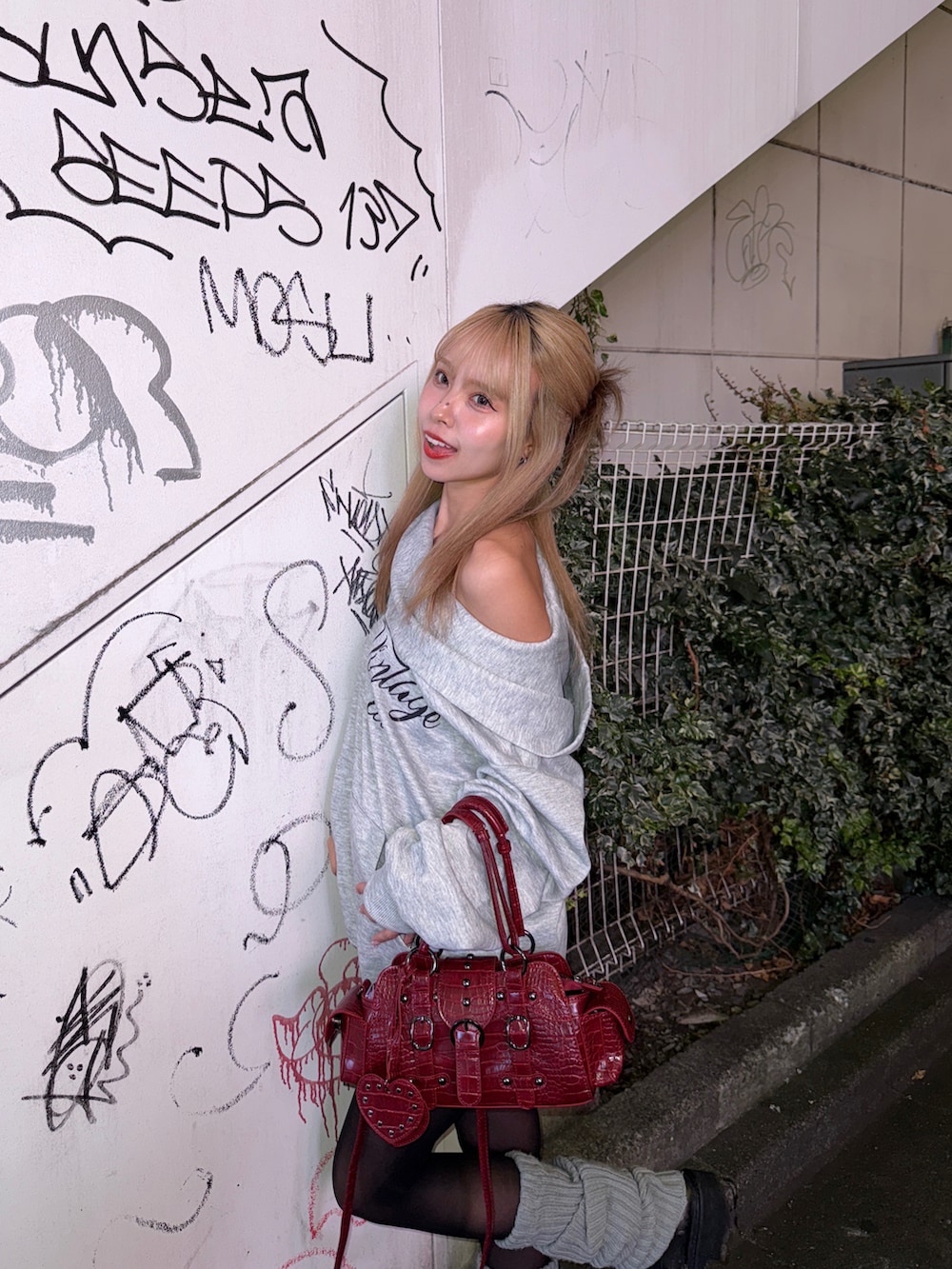 グレー系のトップス、レッド系のバッグを着用したレディースの秋コーディネートの3枚目の写真