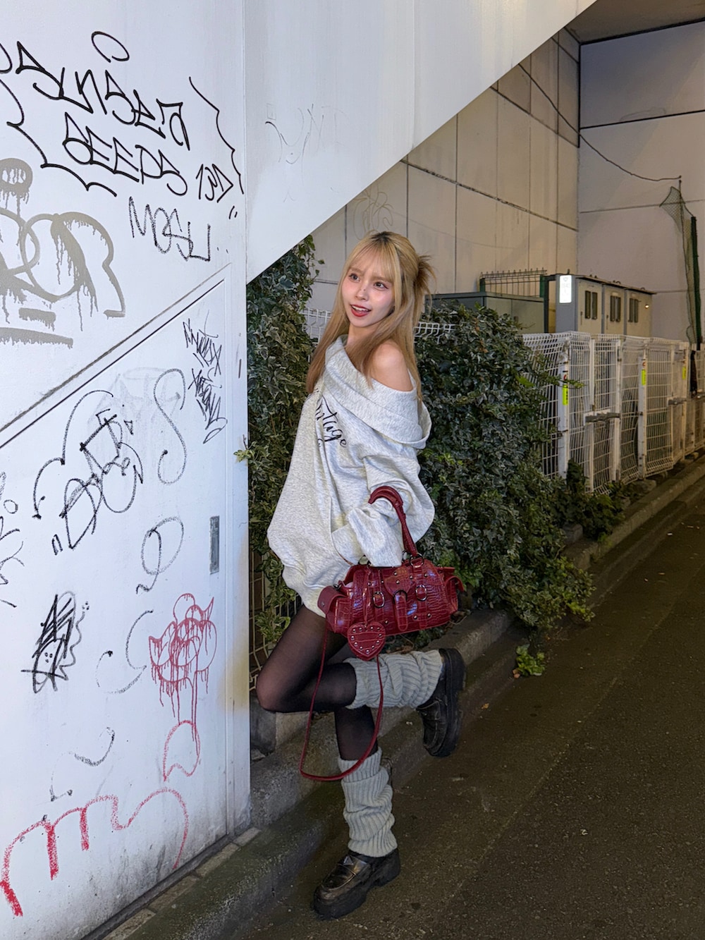 グレー系のトップス、レッド系のバッグを着用したレディースの秋コーディネートの2枚目の写真