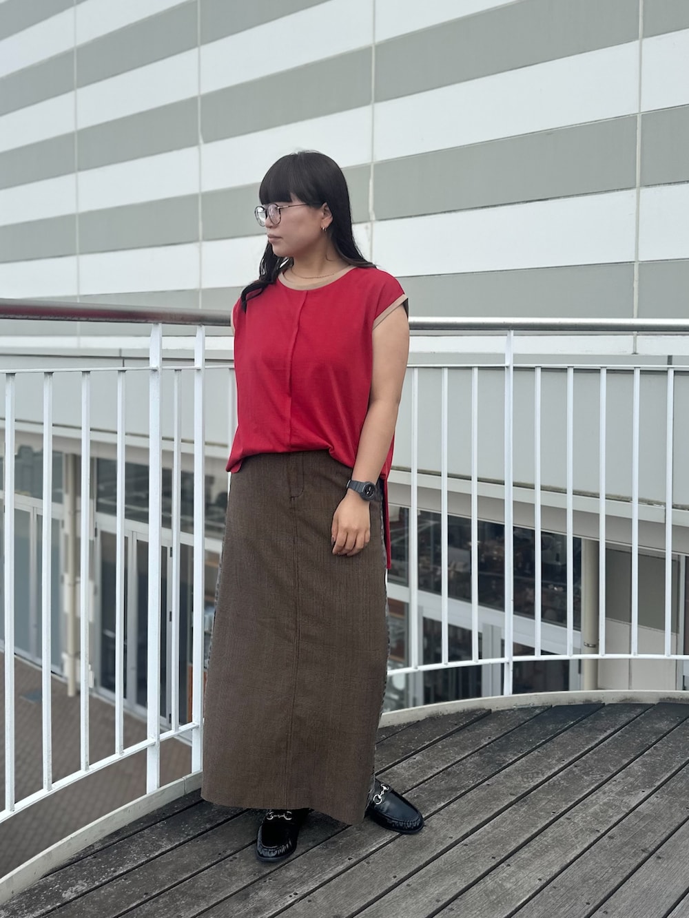 レッド系のTシャツ/カットソー、ブラック系のスカート、ブラウン系のローファーを着用したレディースの夏コーディネートの2枚目の写真