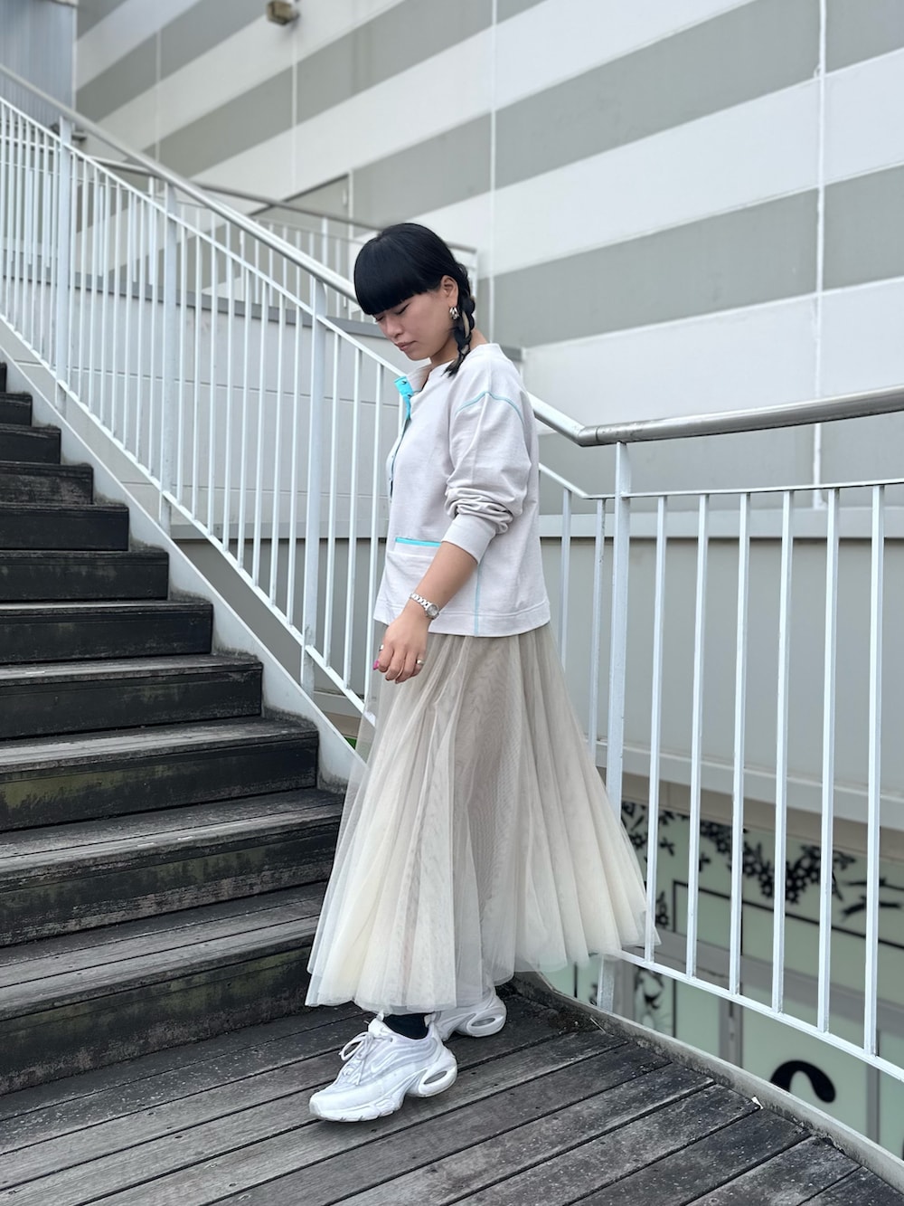 グレー系のカーディガン/ボレロ、ベージュ系のスカート、ホワイト系のスニーカーを着用したレディースの冬コーディネートの2枚目の写真