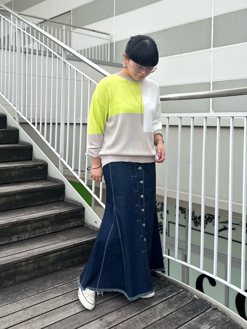 ブルー系のデニムスカート、グレー系のニット/セーター、ホワイト系のスニーカーを着用したレディースの冬コーディネートの2枚目の写真