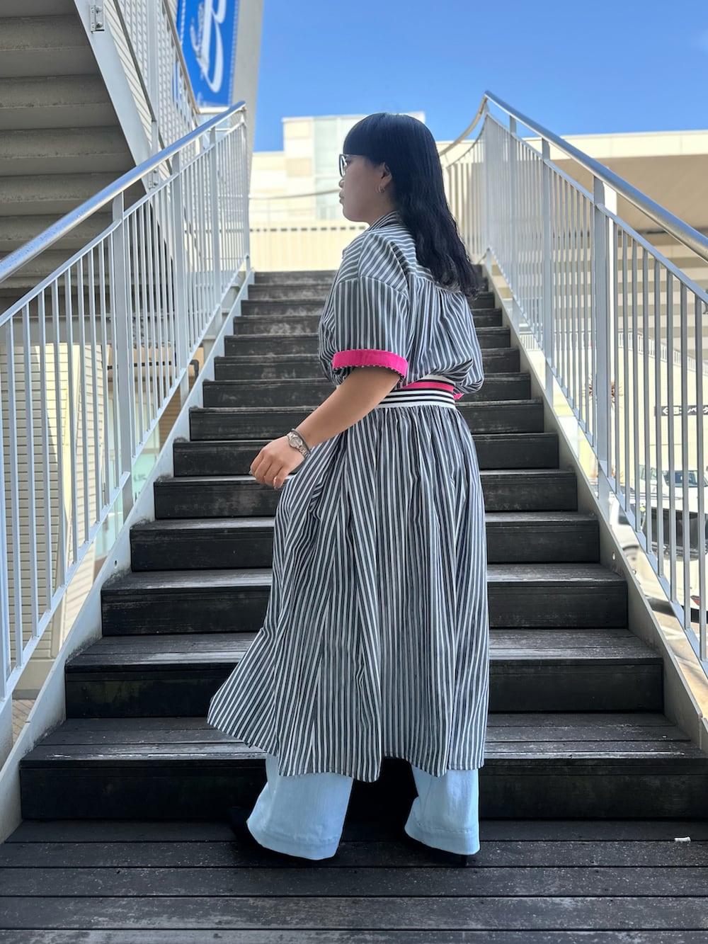 ブラック系のワンピース、ブルー系のデニムパンツを着用したレディースの春コーディネートの3枚目の写真