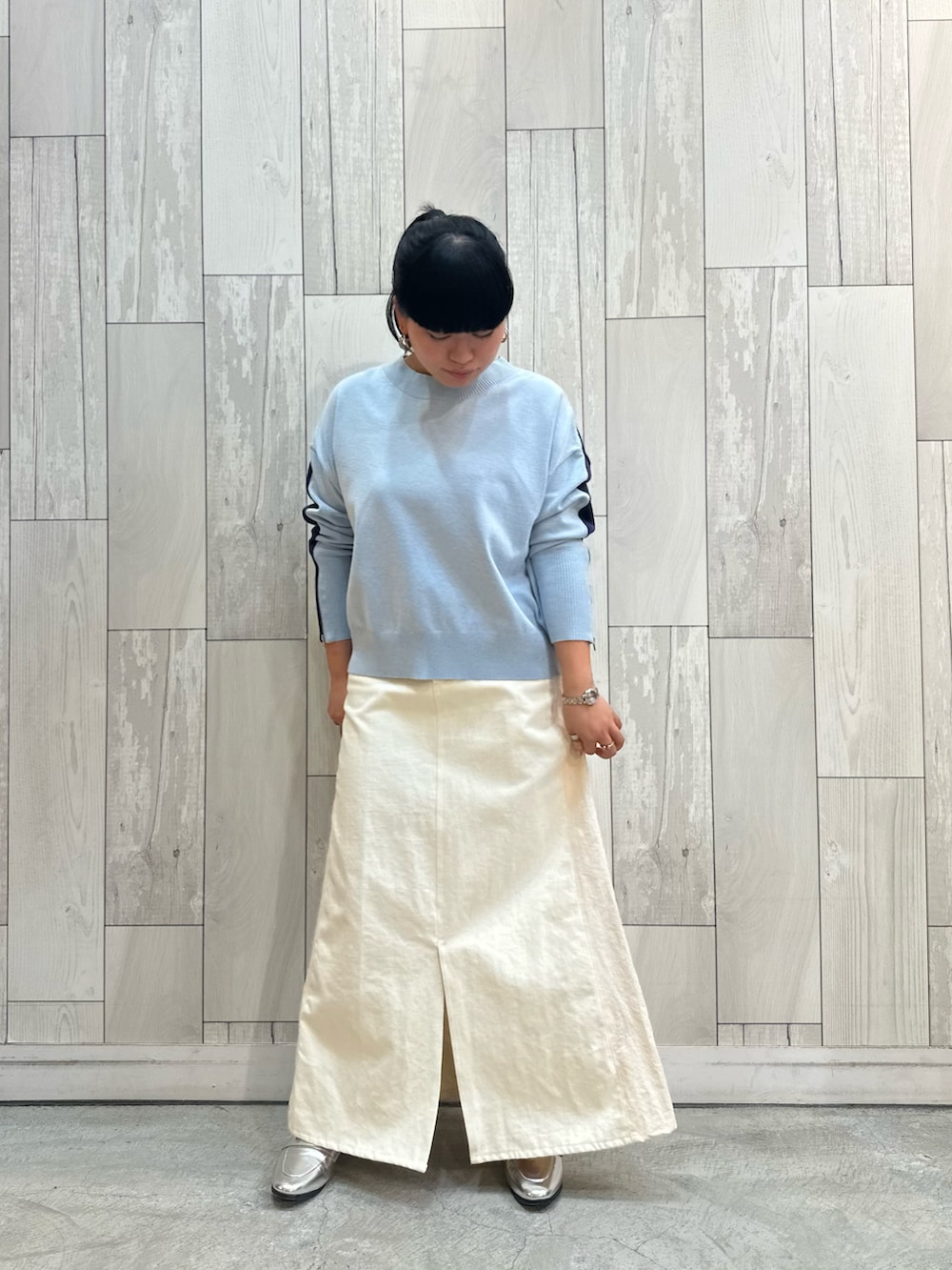 ブルー系のニット/セーター、ホワイト系のデニムスカート、シルバー系のローファーを着用したレディースの冬コーディネートの2枚目の写真