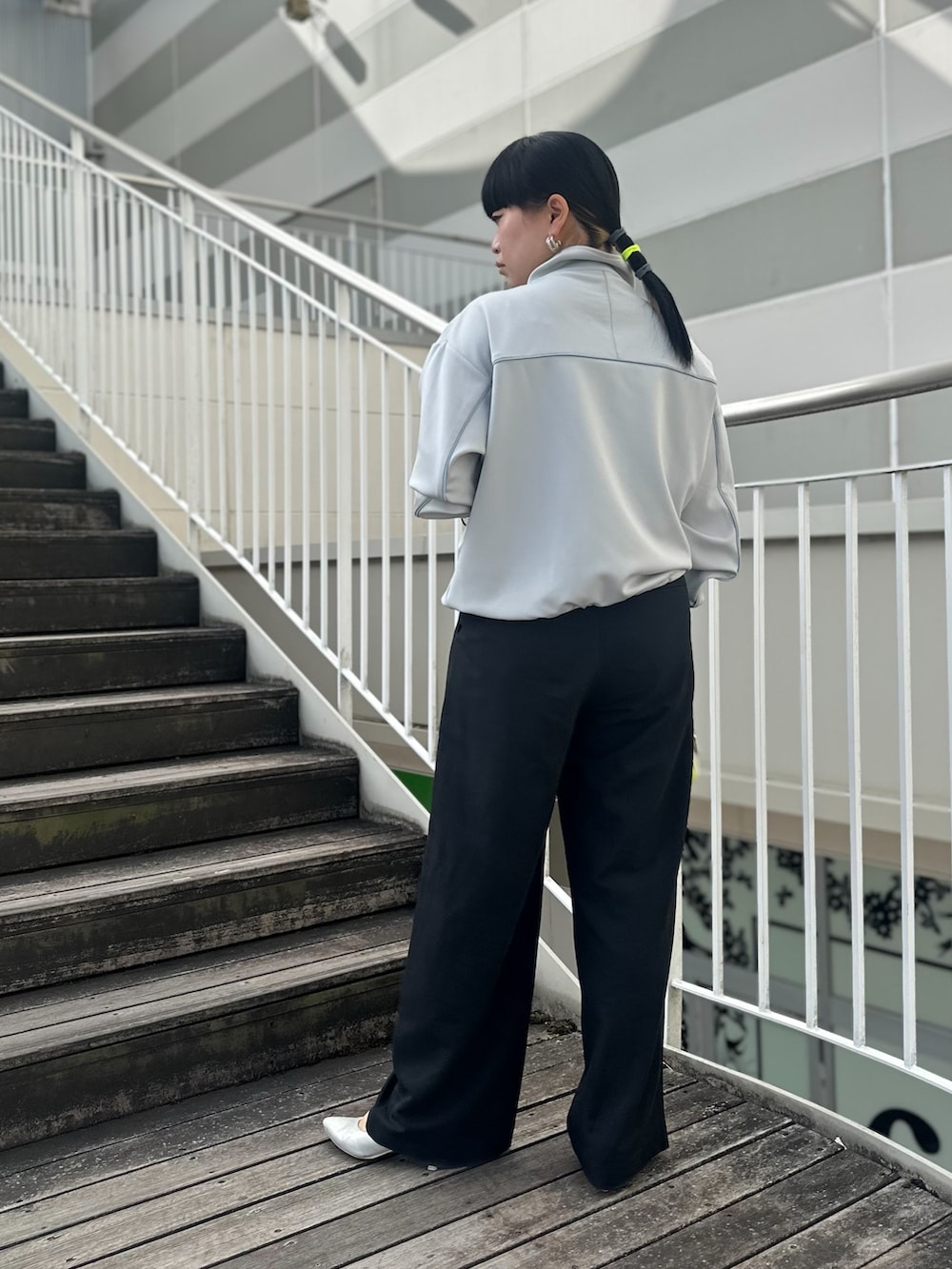 グレー系のその他アウター、ブラック系のスラックス、イエロー系のカードケースを着用したレディースの春コーディネートの3枚目の写真