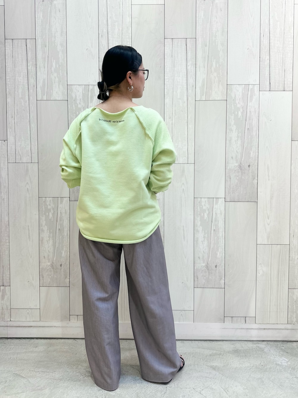 グリーン系のスウェット、グレー系のスラックスを着用したレディースの春コーディネートの3枚目の写真