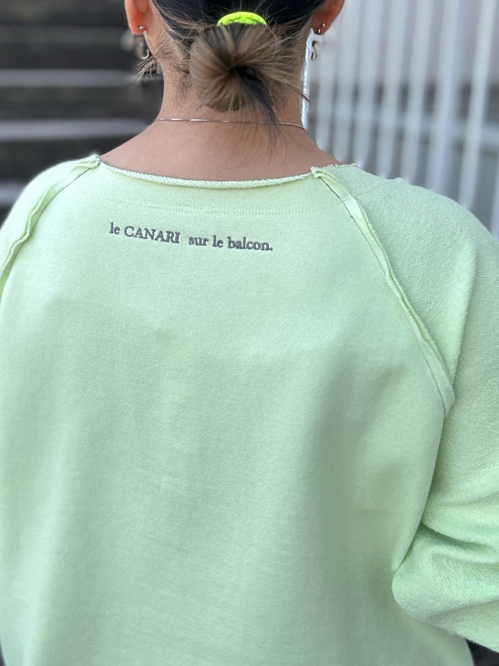 グリーン系のスウェット、グレー系のスカート、ホワイト系のスニーカーを着用したレディースの冬コーディネートの4枚目の写真