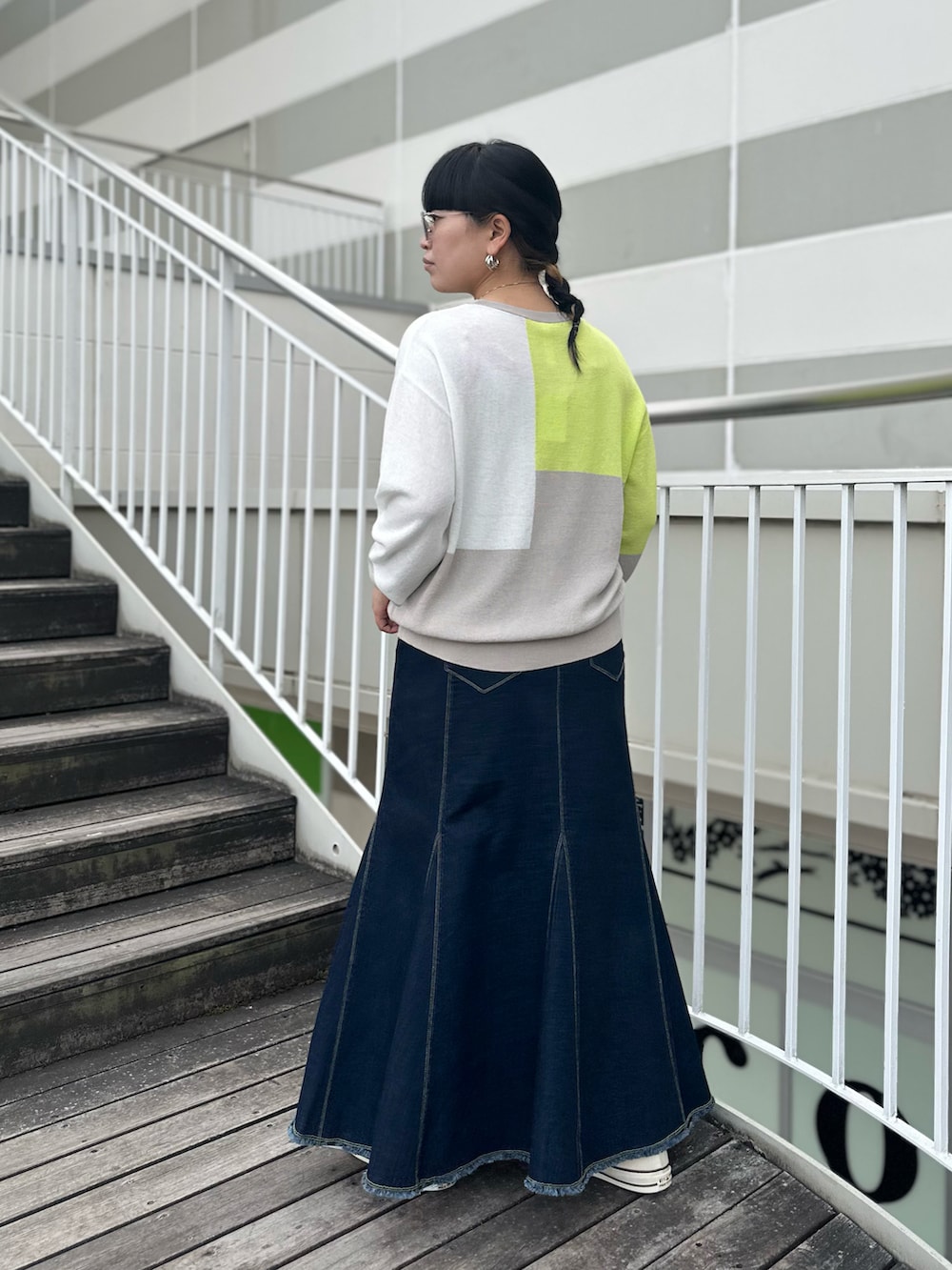 ブルー系のデニムスカート、グレー系のニット/セーター、ホワイト系のスニーカーを着用したレディースの冬コーディネートの3枚目の写真