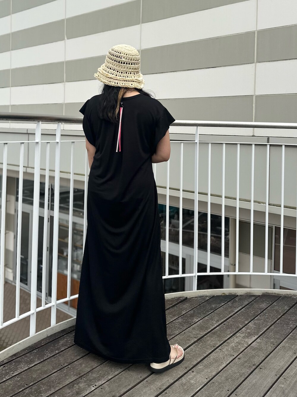 ブラック系のワンピース、ベージュ系のサンダル、ベージュ系のハットを着用したレディースの夏コーディネートの3枚目の写真
