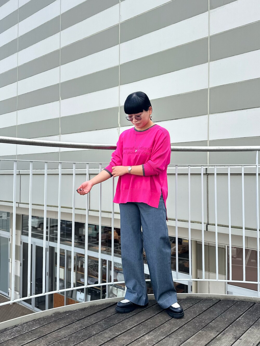 ピンク系のニット/セーター、ブラック系のブーツ、グレー系のデニムパンツを着用したレディースの秋コーディネートの2枚目の写真