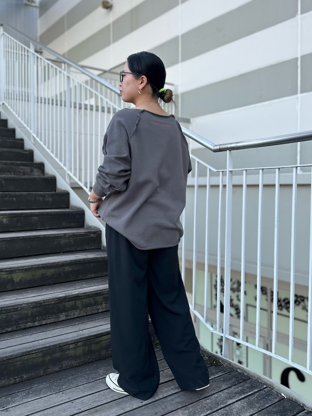 グレー系のスウェット、ブラック系のスラックス、ホワイト系のスニーカーを着用したレディースの冬コーディネートの4枚目の写真