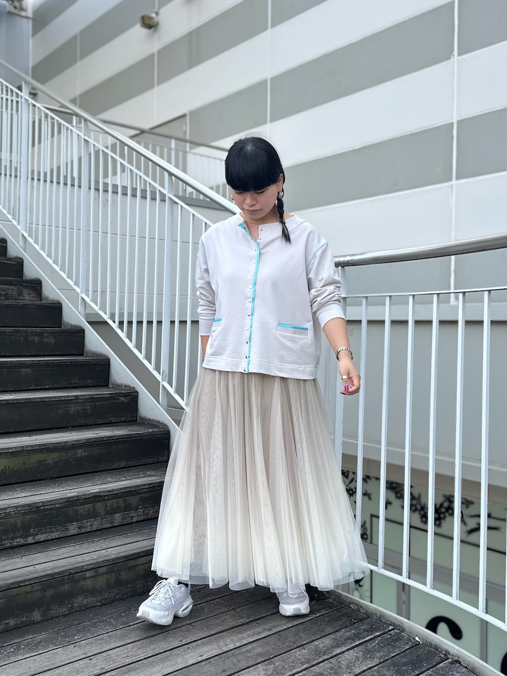 グレー系のカーディガン/ボレロ、ベージュ系のスカート、ホワイト系のスニーカーを着用したレディースの冬コーディネートの3枚目の写真