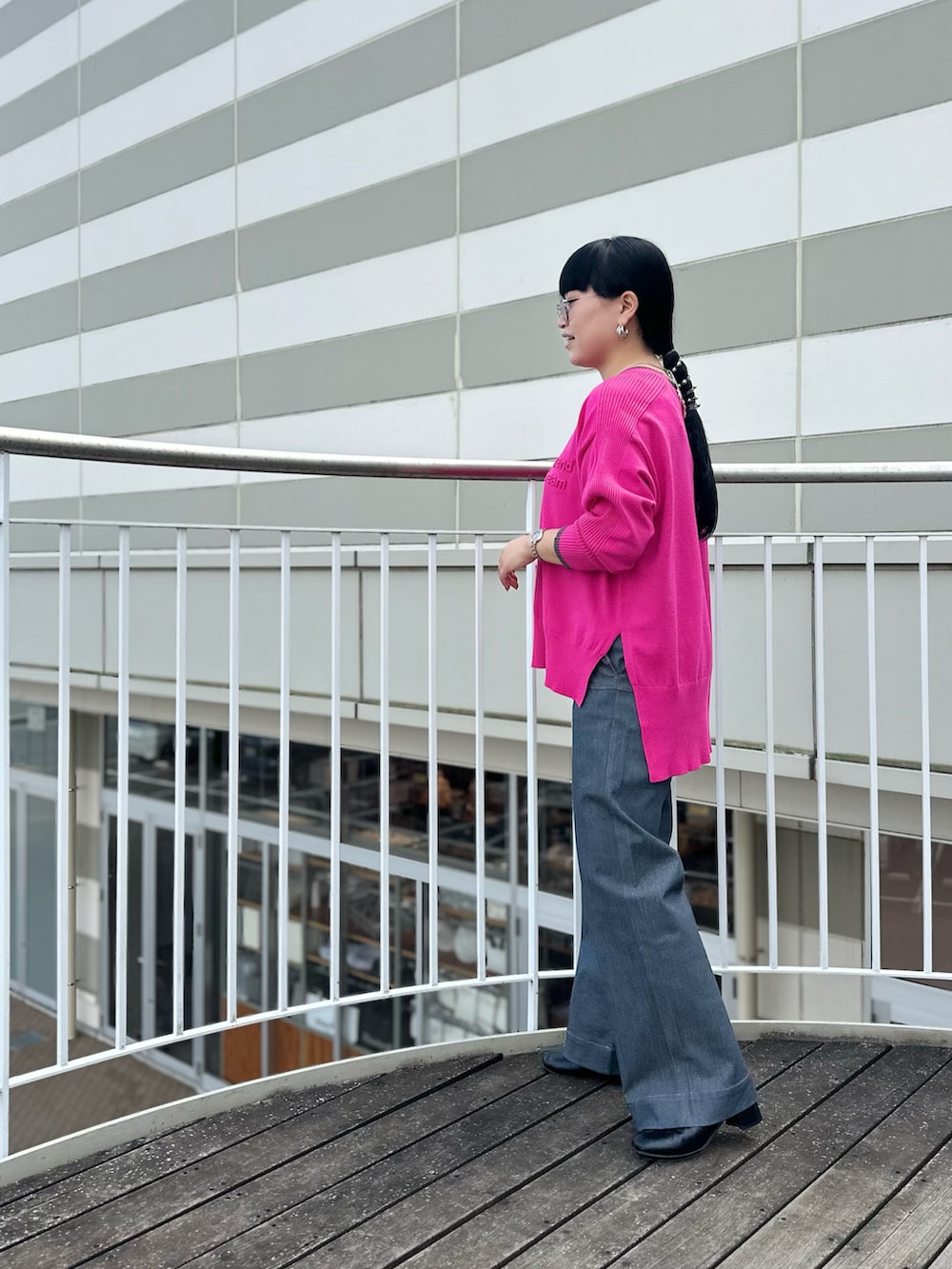 ピンク系のニット/セーター、ブラック系のブーツ、グレー系のデニムパンツを着用したレディースの秋コーディネートの4枚目の写真