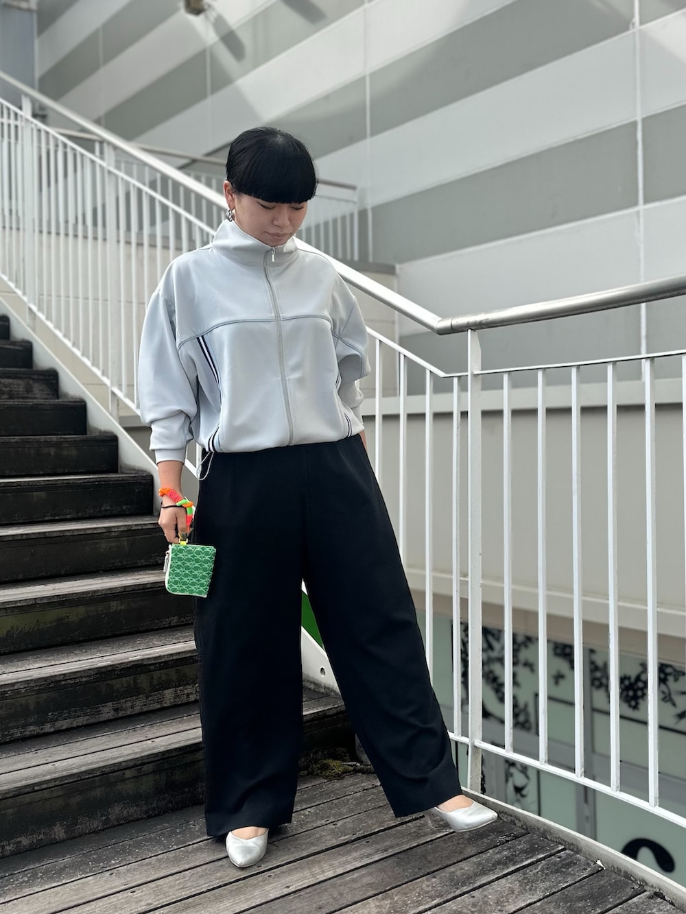 グレー系のその他アウター、ブラック系のスラックス、イエロー系のカードケースを着用したレディースの春コーディネートの2枚目の写真