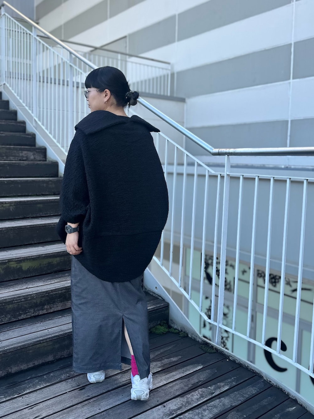 ブラック系のTシャツ/カットソー、グレー系のスカート、ホワイト系のスニーカーを着用したレディースの秋コーディネートの2枚目の写真