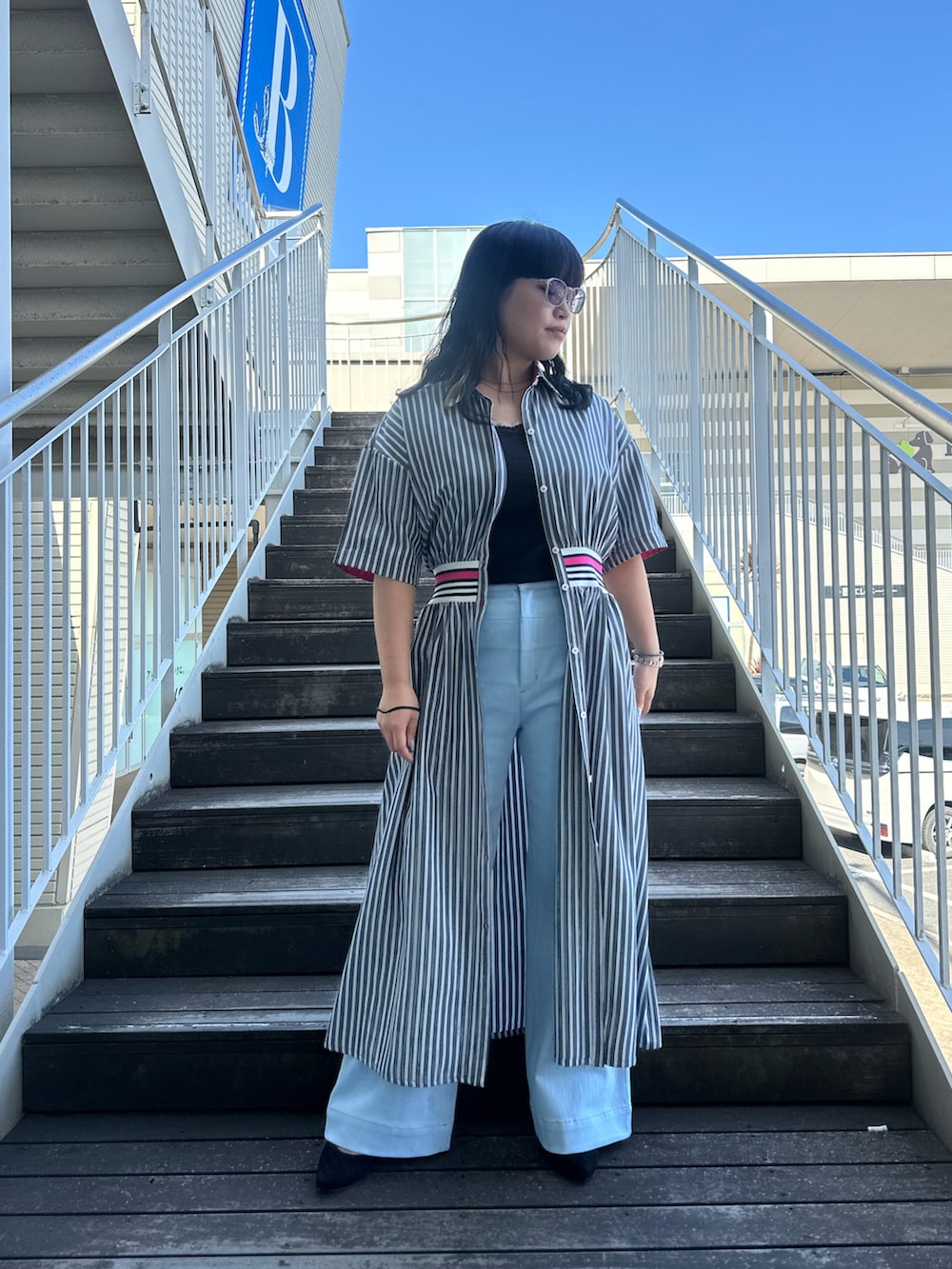 ブラック系のワンピース、ブルー系のデニムパンツを着用したレディースの春コーディネートの4枚目の写真