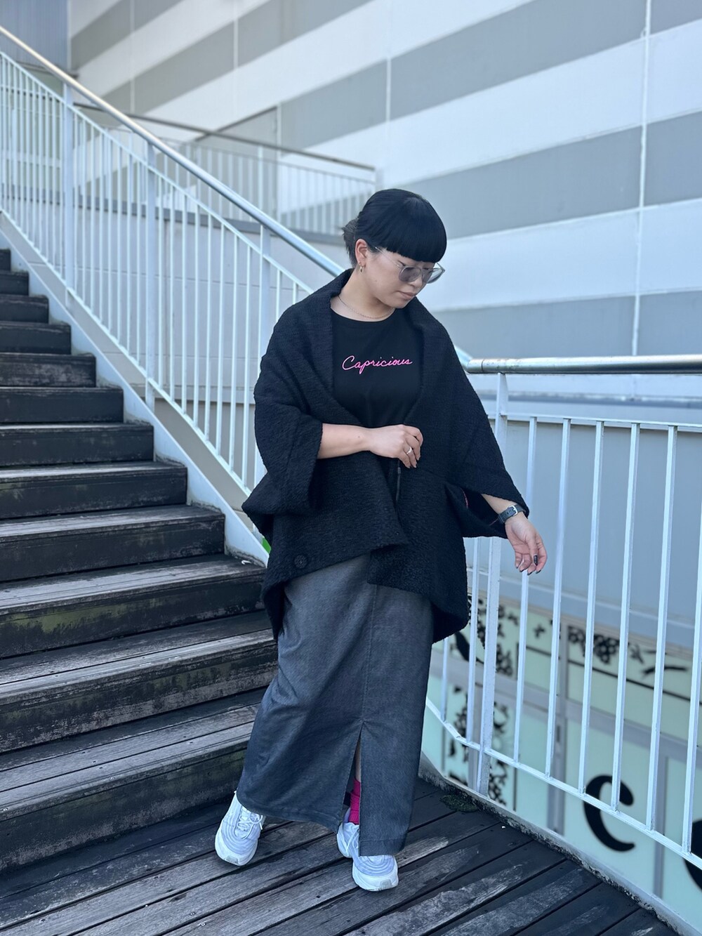 ブラック系のTシャツ/カットソー、グレー系のスカート、ホワイト系のスニーカーを着用したレディースの秋コーディネートの3枚目の写真