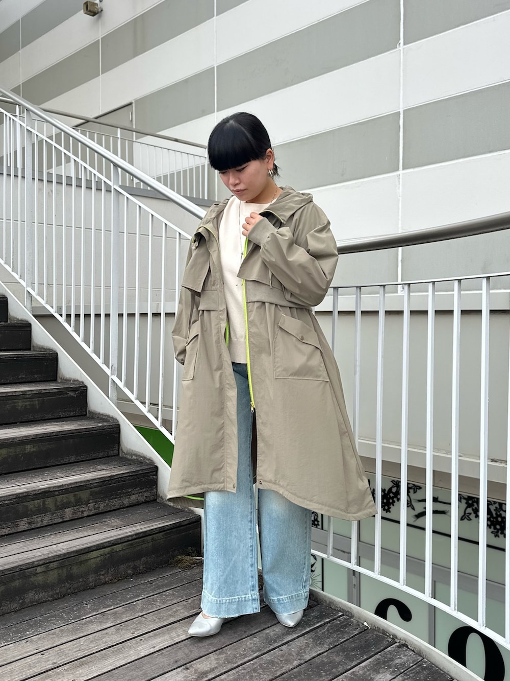 グリーン系のミリタリージャケット、ホワイト系のニット/セーター、ブルー系のデニムパンツを着用したレディースの冬コーディネートの2枚目の写真