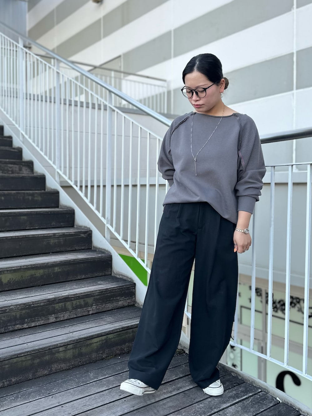 グレー系のスウェット、ブラック系のスラックス、ホワイト系のスニーカーを着用したレディースの冬コーディネートの2枚目の写真