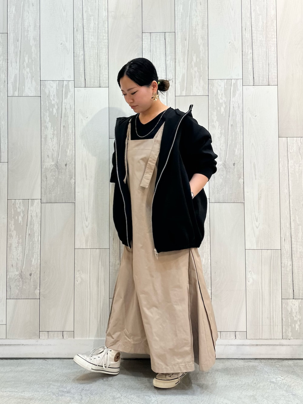 ベージュ系のワンピース、ブラック系のパーカー、ホワイト系のスニーカーを着用したレディースの冬コーディネートの2枚目の写真