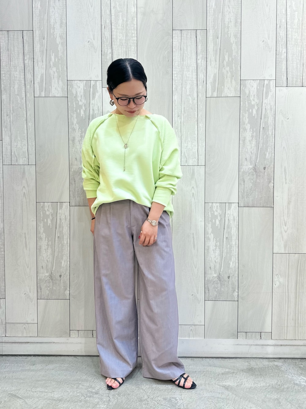 グリーン系のスウェット、グレー系のスラックスを着用したレディースの春コーディネートの2枚目の写真