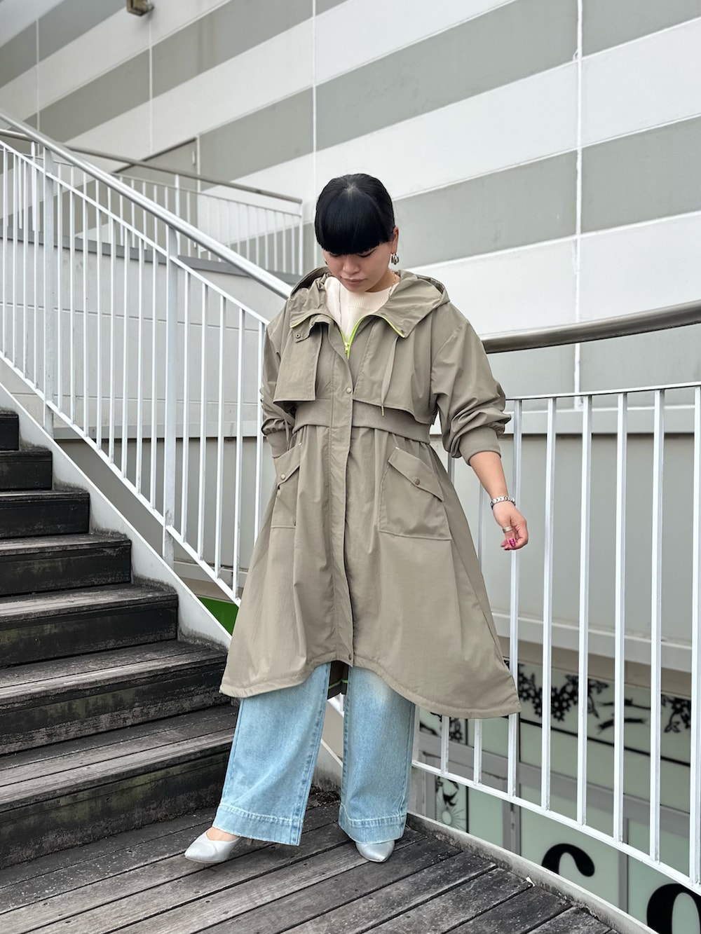 グリーン系のミリタリージャケット、ホワイト系のニット/セーター、ブルー系のデニムパンツを着用したレディースの冬コーディネートの4枚目の写真