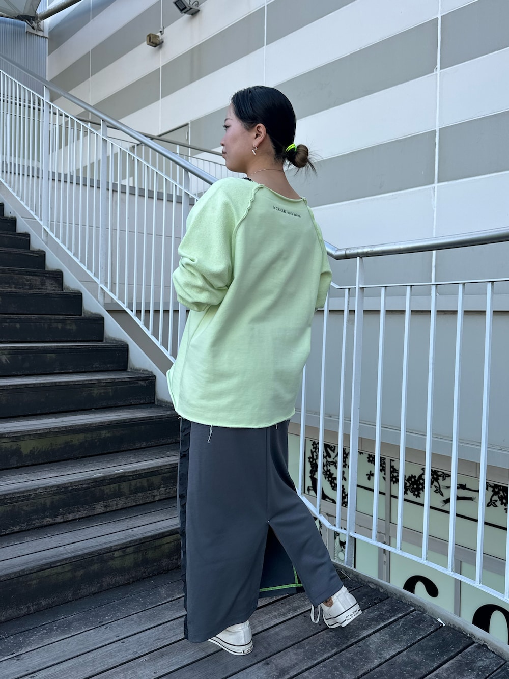 グリーン系のスウェット、グレー系のスカート、ホワイト系のスニーカーを着用したレディースの冬コーディネートの3枚目の写真